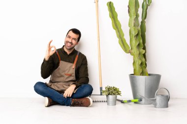 Bahçıvan içeride yerde oturuyor. Parmaklarıyla 