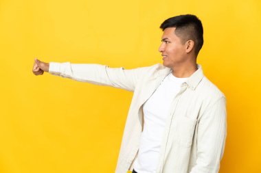 Young Ecuadorian man isolated on yellow background giving a thumbs up gesture