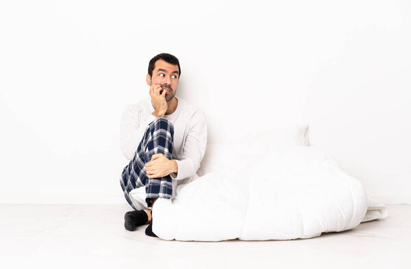 Caucasian man in pajamas sitting on the floor at indoors is a little bit nervous