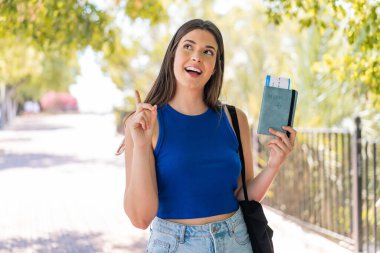 Dışarıda pasaport tutan genç ve güzel Brezilyalı bir kadın çözümü bulmak için parmağını kaldırıyor.