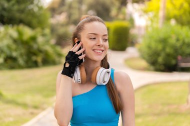 Açık havada giyinen ve cep telefonuyla sohbet eden genç ve güzel bir kız.