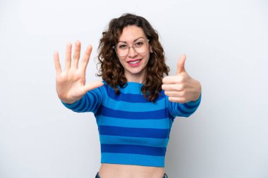 Beyaz arka planda izole edilmiş beyaz tenli genç kadın parmaklarıyla altısını sayıyor.