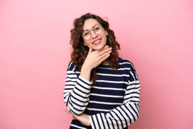 Pembe arka planda izole edilmiş genç beyaz kadın mutlu ve gülümsüyor.