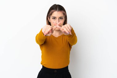 Beyaz arka planda izole edilmiş genç beyaz bir kadın bir eylemi durdurmak için el hareketi yapıyor.