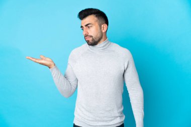 İzole edilmiş mavi arkaplan üzerinde beyaz bir adam boşluğu kuşkularla dolduruyor