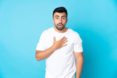İzole edilmiş mavi arka planı olan beyaz bir adam sağa bakarken şaşırmış ve şok olmuştu.