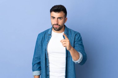 İzole edilmiş mavi arka plan üzerinde beyaz bir adam hayal kırıklığına uğramış ve ön tarafı işaret ediyor.