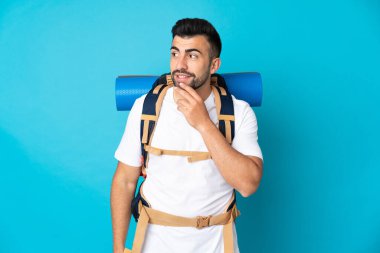 Genç dağcı mavi arka plan üzerinde gülümserken yukarı bakıyor