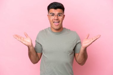 Yüzünde şok ifadesi olan, pembe arka planda izole edilmiş beyaz, yakışıklı bir genç.