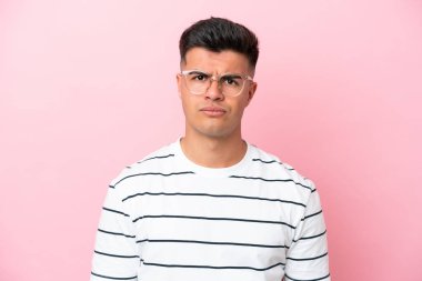 Young caucasian handsome man isolated on pink background With glasses