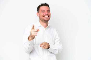 Beyaz arka planda izole edilmiş beyaz, yakışıklı genç adam şaşırmış ve ön tarafı işaret ediyor.