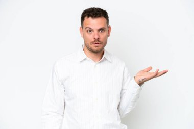 Beyaz arka planda izole edilmiş beyaz, yakışıklı genç bir adam şüpheli hareketlerde bulunuyor.