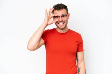 Beyaz arka planda izole edilmiş beyaz tenli yakışıklı bir adam parmaklarıyla işaret veriyor.