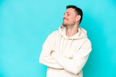 Genç beyaz yakışıklı adam mavi arka planda izole edilmiş mutlu ve gülümsüyor.