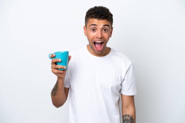 Young Brazilian man holding cup of coffee isolated on white background with surprise and shocked facial expression