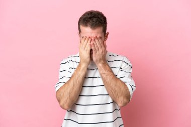 Pembe arka planda izole edilmiş, yorgun ve hasta bir ifadeyle genç beyaz bir adam.