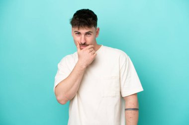 Kafkasyalı yakışıklı genç adam mavi arka planda soyutlanmış düşünüyor.