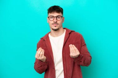 Beyaz tenli yakışıklı adam mavi arka planda izole edilmiş para hareketi yapıyor ama mahvolmuş.