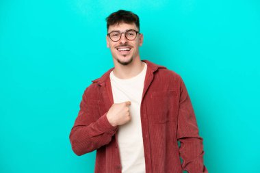 Mavi arka planda yalıtılmış beyaz, yakışıklı, şaşırtıcı bir yüz ifadesi olan genç adam.