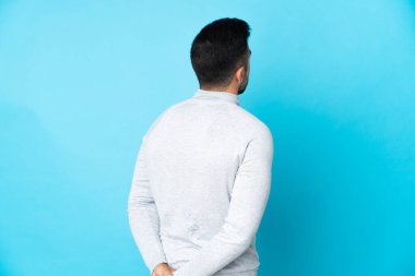 Kafkas adam izole edilmiş mavi arka planda ve geriye bakıyor