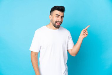 İzole edilmiş mavi arkaplan üzerinde beyaz bir adam parmağı yana doğru gösteriyor.