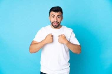 Yüzünde sürpriz ifade olan, izole edilmiş mavi arka planda beyaz bir adam.