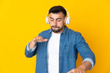 İzole edilmiş sarı arka plan üzerinde beyaz bir adam müzik ve dans dinliyor.