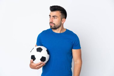 Yakışıklı genç futbolcu yalıtılmış duvarın üzerinden yan tarafa bakıyor.