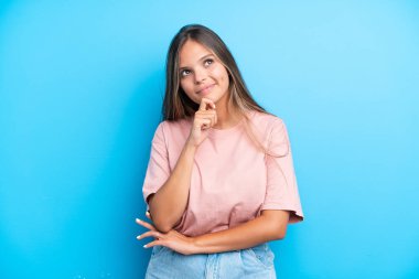 Genç beyaz kadın mavi arka planda izole edilmiş ve yukarı bakıyor.