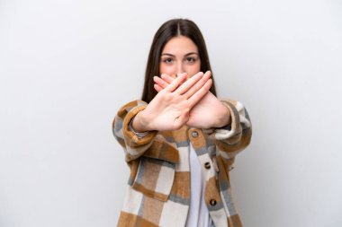 Beyaz arka planda izole edilmiş genç bir kız bir hareketi durdurmak için eliyle jest yapıyor.