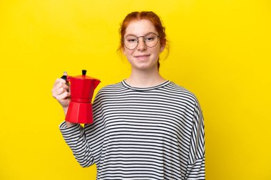 Sarı arka planda izole edilmiş kahve fincanı tutan genç, kırmızı bir kadın. Gülümsüyor.