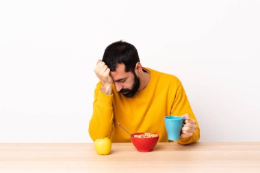 Kafkasyalı bir adam baş ağrısıyla kahvaltı yapıyor..