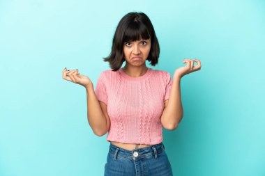 Mavi arka planda izole edilmiş genç melez kadın ellerini kaldırırken şüpheye düşüyor.