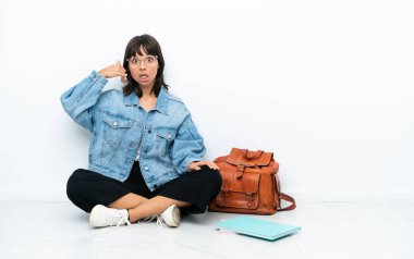 Beyaz arka planda izole bir katta oturan genç bir bayan telefon jesti yapıyor. Bana geri dönüş işareti ver.