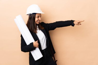 İzole edilmiş arka plan üzerinde planları olan genç mimar kadın parmak kaldırıyor ve bir ürün sunuyor.