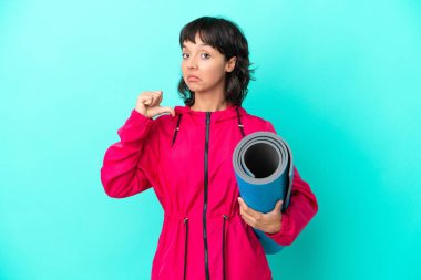 Mavi arka planda kendini beğenmiş ve gururlu bir haldeyken yoga derslerine giden genç bir kız.