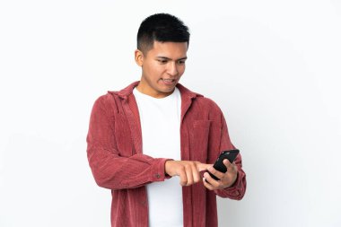 Genç Ekvadorlu adam beyaz arka planda izole edilmiş cep telefonuyla bir mesaj ya da e-posta gönderiyor