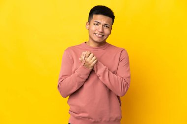 Genç Ekvadorlu adam sarı arka planda izole edilmiş gülüyor.