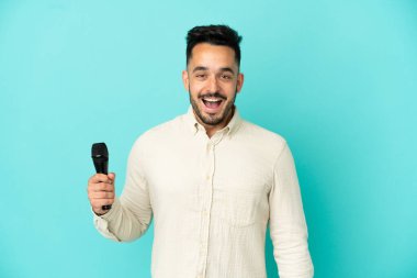 Beyaz tenli genç şarkıcı, mavi arka planda mahsur kalmış, şaşırmış bir yüz ifadesi var.