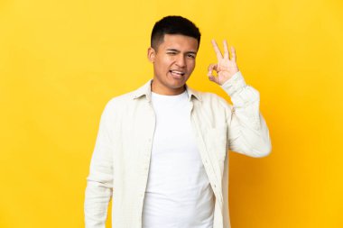 Young Ecuadorian man isolated on yellow background showing ok sign with fingers