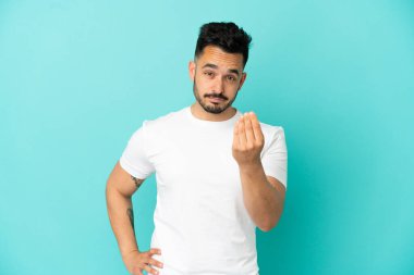 Mavi arka planda izole edilmiş genç beyaz adam İtalyan jestleri yapıyor.