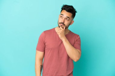 Kafkasyalı genç adam mavi arka planda izole edilmiş ve yukarı bakıyor.