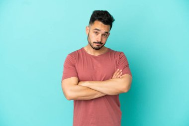 Mavi arka planda izole edilmiş genç beyaz bir adam üzgün hissediyor.