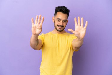 Mor arka planda izole edilmiş beyaz bir adam dokuz parmaklı sayıyor.