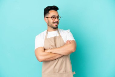 Restoran garsonu beyaz adam mavi arka planda izole edilmiş mutlu ve gülümsüyor.