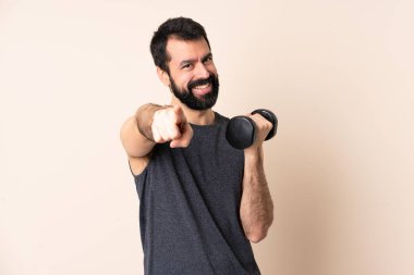 Beyaz sakallı sporcu halter kaldırıyor izole arka plan üzerinde mutlu bir ifadeyle ön tarafı işaret ediyor.