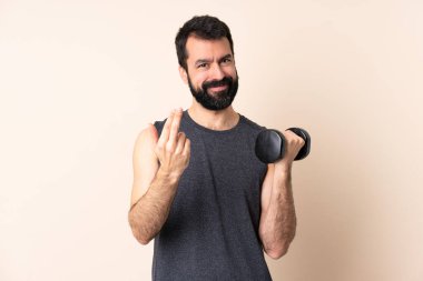 Beyaz sakallı sporcu arka planda halter kaldırıyor. Eli ile gelmesi için davet ediyor. Gelmene sevindim.