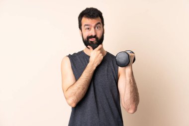 Beyaz sakallı sporcu izole edilmiş arka planda ağırlık kaldırıyor.