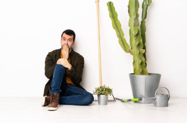 Bahçıvan içeride yerde oturuyor. Ağzını eliyle kapatıyor.