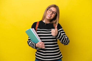 Young student woman isolated on yellow background background giving a thumbs up gesture